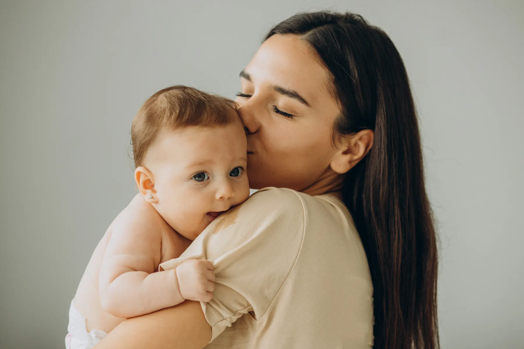 Madre sonriendo junto a su bebé en casa