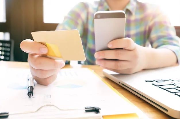 Una persona consulta su teléfono junto a una laptop antes de comprar